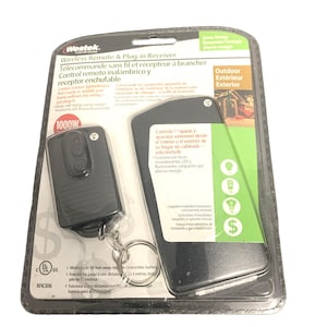 Pode incluir: Um controle remoto sem fio e receptor plug-in Westek preto, embalado em uma embalagem blister transparente. O pacote inclui um controle remoto com chaveiro e uma unidade receptora. O texto indica que controla luzes e aparelhos externos.