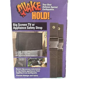 May include: A black "Quake Hold" box with a safety strap for big screen TVs or appliances. The box features text in English and Spanish, with images of the product in use. The strap has a buckle and is designed to prevent toppling during earthquakes.