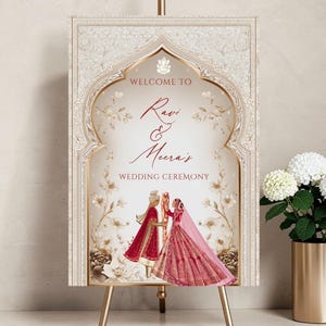 Personalised Hindu wedding welcome sign printed on 3mm foamex featuring Ganesha symbol, illustrated bride in red lehenga and groom in red sherwani beneath ornate ivory and gold Mughal arch with delicate floral linework