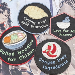 May include: Four embroidered patches with black backgrounds. One circular patch shows a wonton with the text Crying over spilt wontons. A hexagonal patch features a blue bird in a bowl with Love for All Seasons. A circular patch shows ramen with Pulled Noodles for Shizun. A circular patch shows red chili peppers with Congee Prep Ingredients.