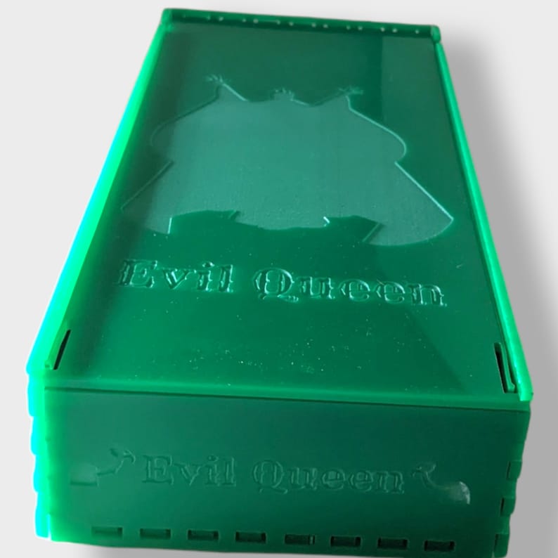 Pu&ograve; includere: Una scatola in acrilico verde con le parole "Evil Queen" stampate sul davanti e sulla parte superiore. La scatola ha un design ritagliato sul davanti.