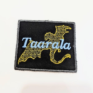 May include: A black fabric patch with a yellow embroidered dragon design and the word "Taarala" in blue embroidery.