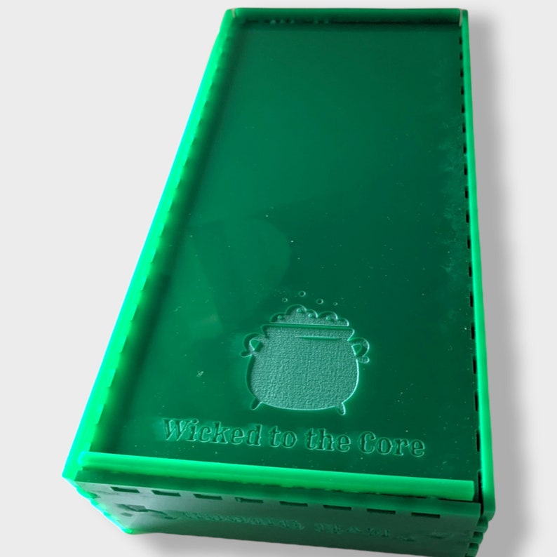 Pu&ograve; includere: Una scatola verde con un calderone e il testo "Wicked to the Core" sul davanti.