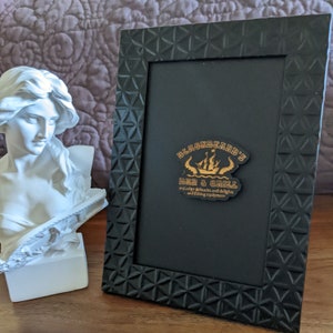 May include: Black picture frame with a gold logo that says "Blackbeard's Bar & Grill" and "and other delicacies and delights and fishing equipment".