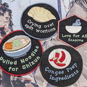 May include: Four embroidered patches with different designs and text. The patches are black with white and colored embroidery. The text on the patches reads: "Crying over spilt wontons", "Pulled Noodles for Shizun", "Love for All Seasons", and "Congee Prep Ingredients".