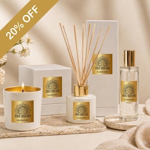 May include: A set of white aromatherapy products with gold detailing, including a candle, diffuser, and perfume bottle. Each item has a gold label with the text "MAKE YOUR AVID HARMONY". The candle is lit, and the diffuser contains wooden reeds.
