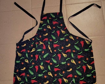 May include: Black kitchen apron with a colorful chili pepper pattern. The apron has adjustable straps and a large pocket.