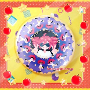 May include: A round, purple button with a cartoon girl wearing sunglasses and making a peace sign. The button has a scalloped edge and is surrounded by cartoon figures and Japanese text. The background is yellow with red apples and stars.