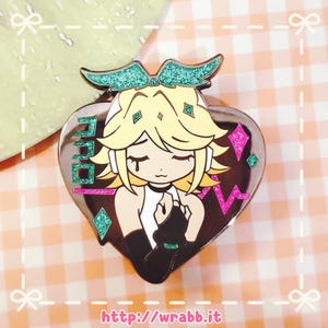 May include: A heart-shaped enamel pin featuring a cartoon character with blonde hair, closed eyes, and a white top. The pin has a teal glitter bow and accents, with the word "700" in teal glitter. The website address "http://wrabb.it" is at the bottom.