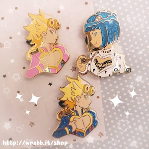 May include: Three enamel pins featuring anime characters. One pin has a character with blonde hair and pink clothing. Another pin has a character with blue hair and a white outfit. The third pin has a character with blonde hair and blue clothing. The website address is at the bottom.