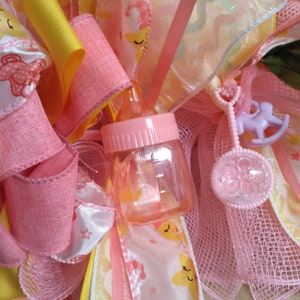 A rare find and one of a kind. A baby shower wreath for a little girl with pink booties and rattlers. Plastic rocking horses and baby bottle image 5