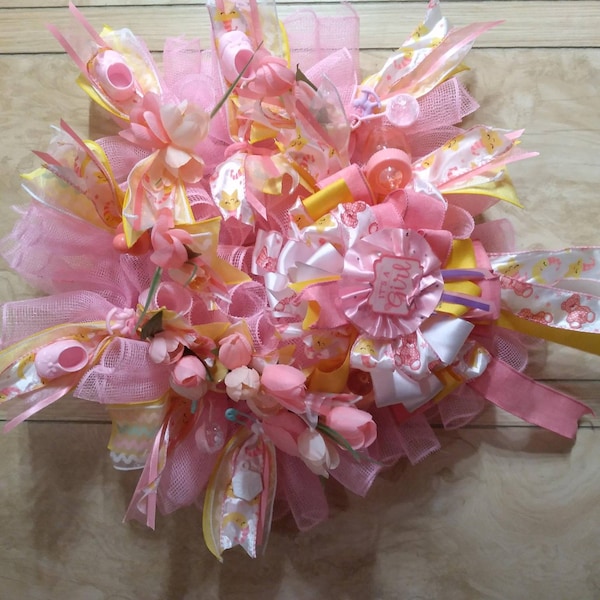 A rare find and one of a kind. A baby shower wreath for a little girl with pink booties and rattlers. Plastic rocking horses and baby bottle