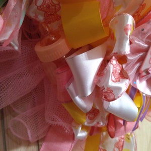 A rare find and one of a kind. A baby shower wreath for a little girl with pink booties and rattlers. Plastic rocking horses and baby bottle image 6