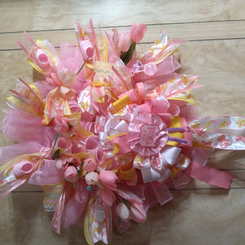 A rare find and one of a kind. A baby shower wreath for a little girl with pink booties and rattlers. Plastic rocking horses and baby bottle image 3