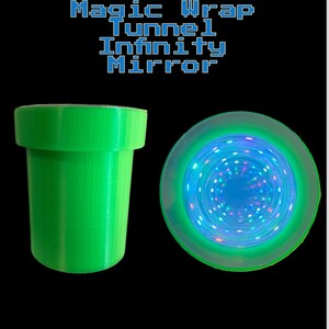 以下が含まれることがあります： 緑色のパイプのような円筒形の物体と、丸い無限ミラー。ミラーは青と緑の光で輝き、トンネル効果を生み出します。「Magic Wrap Tunnel Infinity Mirror」の文字が上に表示されています。