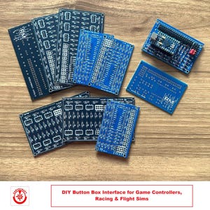 Könnte beinhalten: Eine Sammlung von blauen und schwarzen Leiterplatten mit verschiedenen Komponenten und Text, darunter "RM" und "Pro Micro". Die Platinen sind auf einer Holzoberfläche angeordnet. DIY Button Box Interface für Game Controller, Rennspiele und Flugsimulatoren.