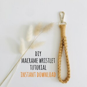 May include: A mustard yellow macrame wristlet with a gold-toned metal lobster clasp. The text reads: DIY MACRAME WRISTLET TUTORIAL INSTANT DOWNLOAD. The wristlet is accompanied by a sprig of dried cream-colored bunny tail grass.