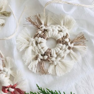 Peut inclure: Une d&eacute;coration en macram&eacute; blanche et dor&eacute;e de forme circulaire avec des d&eacute;tails en franges. L'ornement est fait &agrave; la main et a un style rustique et boh&egrave;me.