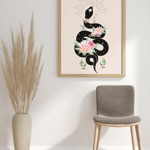 May include: A black snake with a starry pattern is coiled around a bouquet of pink and white flowers. The snake is surrounded by a circle of small stars and a sunburst design. The background is a light peach color.