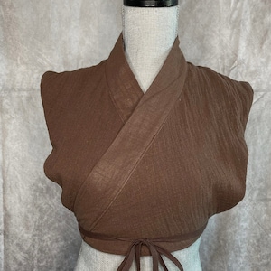 May include: A brown wrap top with a long tie that can be tied in the front or back. The top is made of a soft, textured fabric and has a relaxed fit.