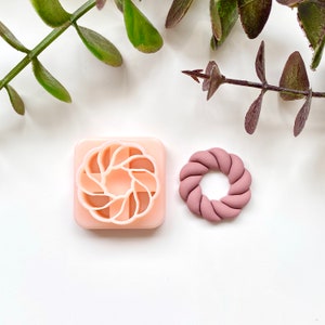 May include: A pink plastic mold for making a decorative wreath shape, and a pink clay wreath.