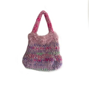 May include: A small, knitted handbag with a pink and purple color scheme. The bag has a fluffy pink trim and pink and white knit handles.