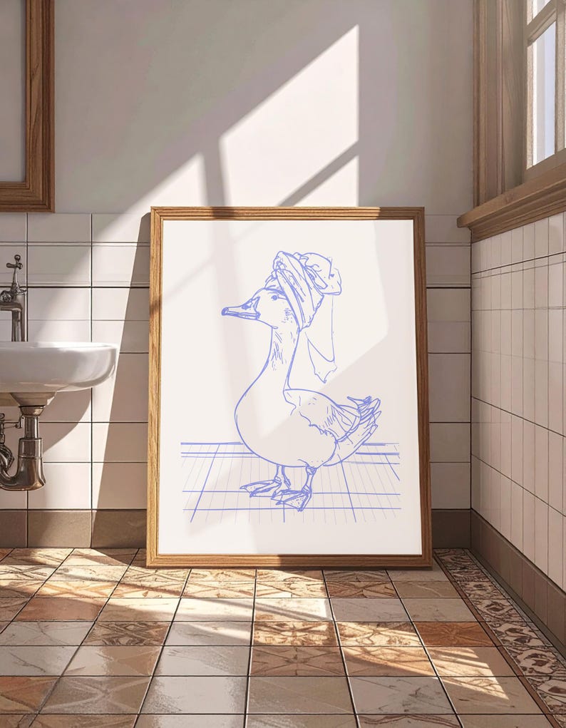 May include: A framed wall art print featuring a blue line drawing of a goose wearing a towel wrapped around its head like a turban. The goose is standing on a grid pattern surface, rendered in a simple, clean illustration style on a white background.