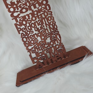 Puede incluir: Una pieza decorativa de madera marr&oacute;n con texto cortado con l&aacute;ser. El texto est&aacute; en una fuente de escritura y parece ser una oraci&oacute;n o una cita inspiradora. La pieza tiene una base rectangular y una secci&oacute;n vertical con el texto.