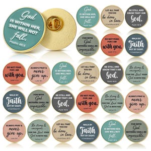 May include: A collection of round enamel pins with gold-colored edges. Each pin features inspirational text from the Bible in a variety of colors, including teal, pink, and gray. The pins have a pin back.
