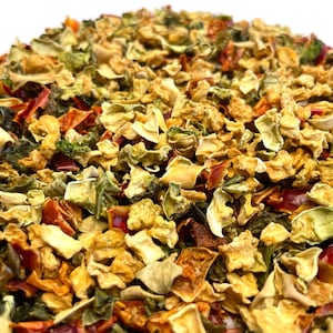 May include: A close-up of a mixture of dried vegetables, including green bell peppers, red bell peppers, and yellow squash.