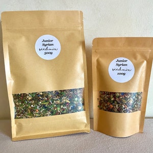 Pu&ograve; includere: Due sacchetti di carta marrone pieni di un mix di semi. Il sacchetto pi&ugrave; grande &egrave; etichettato "Junior Syrian seed mix 500g" e il sacchetto pi&ugrave; piccolo &egrave; etichettato "Junior Syrian seed mix 100g".