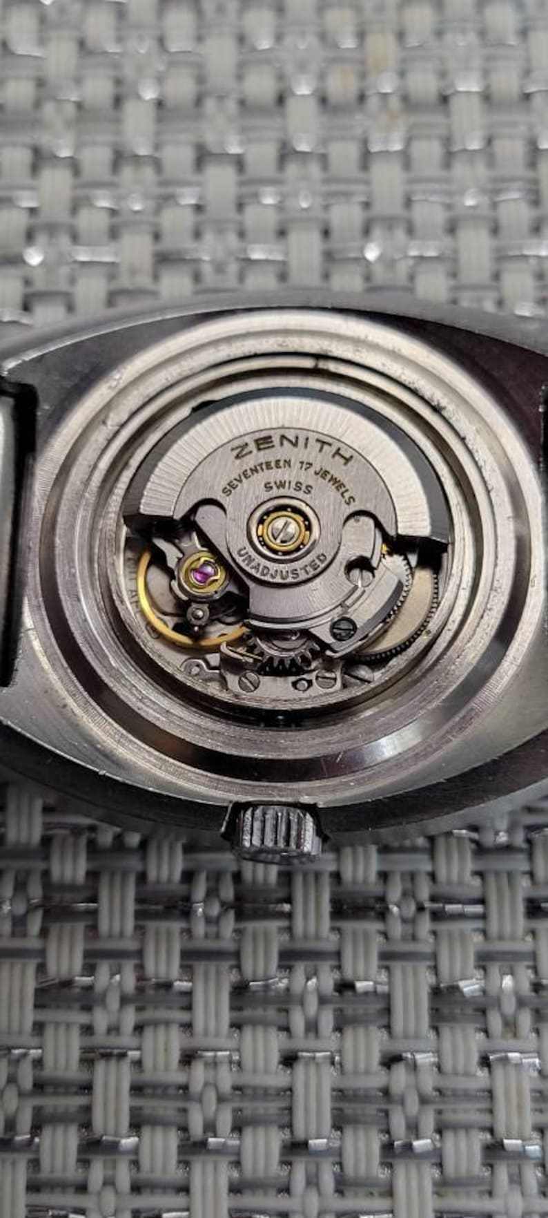 May include: Close-up of a silver Zenith watch movement with the text "Seventeen 17 Jewels Swiss Unadjusted" visible.