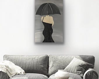 May include: An original painting depicts a woman in a black dress holding a black umbrella. The artwork is set against a gray backdrop, creating a monochromatic aesthetic. The painting is displayed on a white wall above a gray sofa.