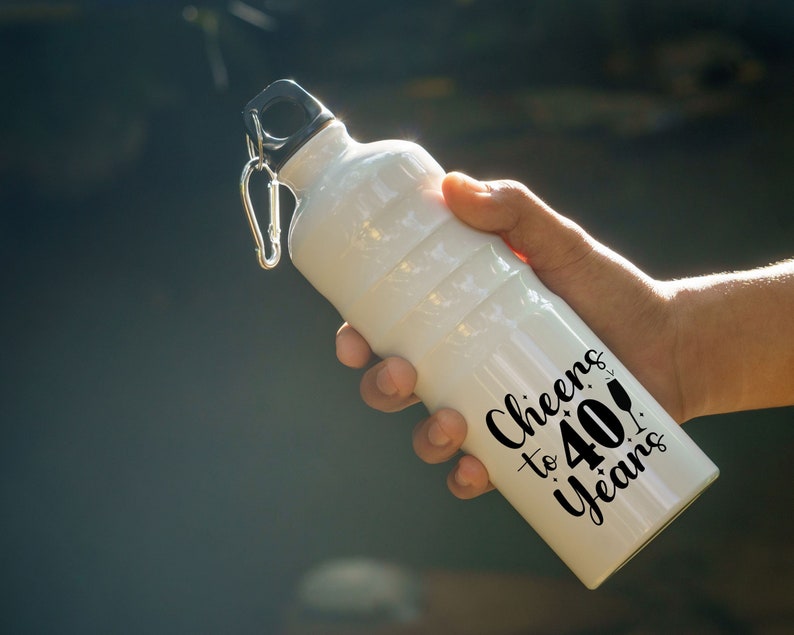 May include: White water bottle with a black lid and a black carabiner clip. The bottle has black text that reads "Cheers to 40 Years!"