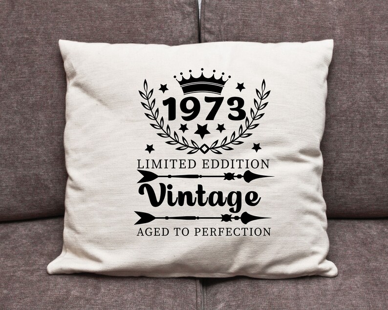 May include: White throw pillow with black text and a crown graphic. The text reads "1973 Limited Edition Vintage Aged to Perfection".