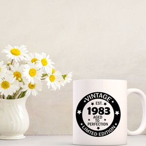 May include: White ceramic mug with a black circle design that says "Vintage Est. 1983 Aged to Perfection Limited Edition".