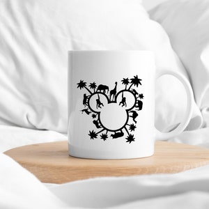 May include: White ceramic mug with a black silhouette of Mickey Mouse's head formed by various animals and palm trees.