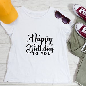 K&ouml;nnte beinhalten: Wei&szlig;es T-Shirt mit schwarzem Text, der "Happy Birthday to You" mit kleinen Herzen und Sternen um den Text herum sagt.