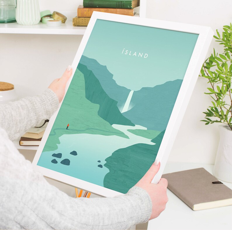 May include: A framed art print featuring a minimalist landscape of Iceland. The artwork depicts a waterfall, mountains, and a small figure on a path, all in shades of green and blue. The word "ISLAND" is at the top.