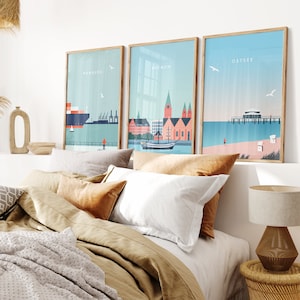 May include: Three framed illustrations of cityscapes with the words "Hamburg", "Bremen", and "Ostsee" printed on each. The illustrations are in a minimalist style with a blue and white color scheme.