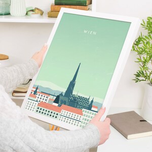 May include: A white framed print with a green background and a stylized illustration of the Vienna skyline. The text "WIEN" is at the top of the print.