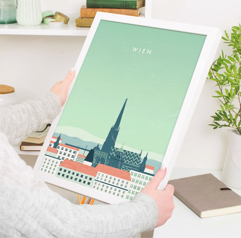 May include: A white framed print with a green background and a stylized illustration of the Vienna skyline. The text "WIEN" is at the top of the print.