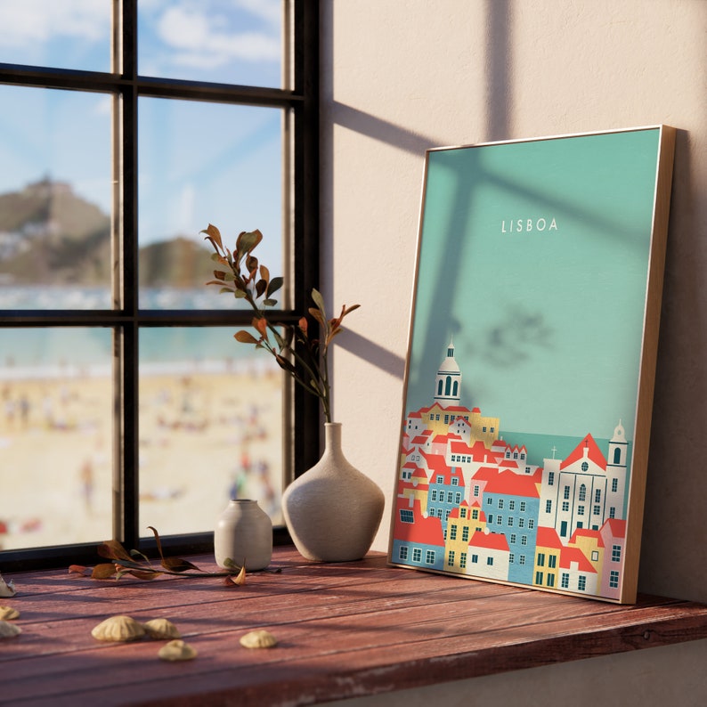 May include: A framed art print featuring a colorful illustration of Lisbon, Portugal, with the city's name in white text. The artwork is displayed on a wooden surface near a window, with a vase and decorative items.
