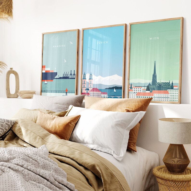 May include: Three framed city skyline prints with a minimalist design. The prints feature the cities of Hamburg, Zurich, and Wien. The prints are hung on a white wall above a bed with brown bedding.