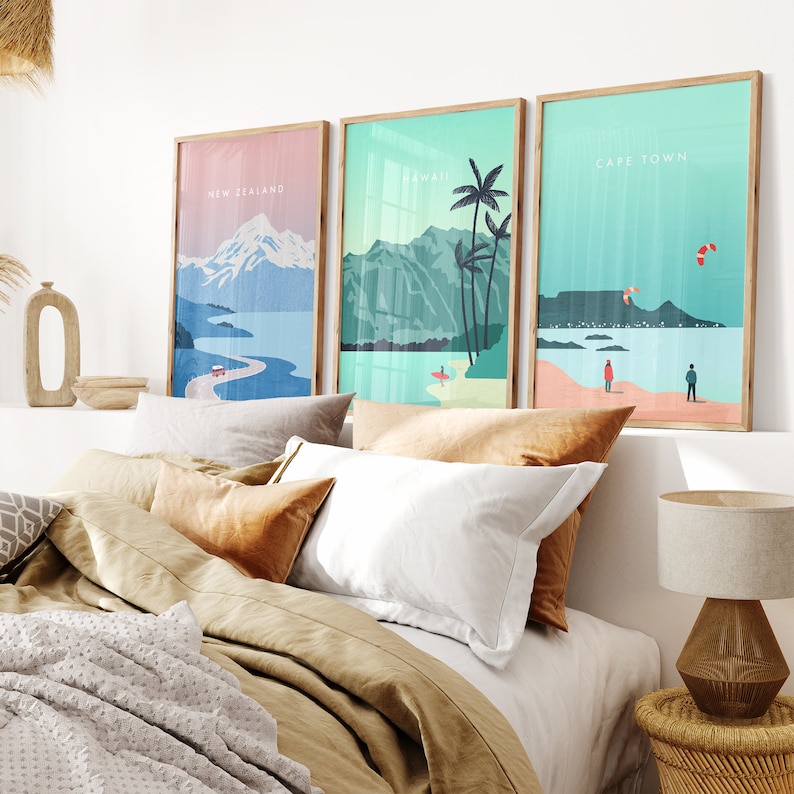 May include: Three framed illustrations of different locations. The first illustration is of New Zealand with a mountain range and a winding road. The second illustration is of Hawaii with palm trees and a beach. The third illustration is of Cape Town with a mountain and a kite surfer.