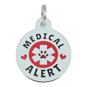 Op de afbeelding: Een zilverkleurige, ronde dierenpenning met de woorden "MEDICAL ALERT" in zwarte letters. Het midden heeft een rood kruis met een pootafdruk en twee rode hartjes. Bovenop zit een kleine zilveren lus voor bevestiging.