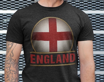 May include: A dark gray t-shirt with a vintage-style graphic of the English flag and the word "ENGLAND" in a gold banner.
