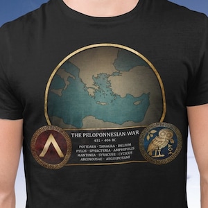Puede incluir: Camiseta negra con un gráfico de un mapa del mar Mediterráneo y el texto "The Peloponnesian War 431 - 404 BC". El gráfico también incluye dos escudos con símbolos.