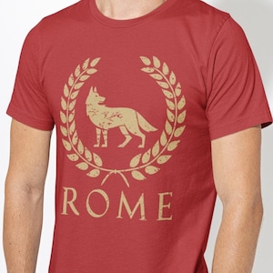 May include: Red t-shirt with a gold wolf inside a laurel wreath and the word "ROME" underneath.