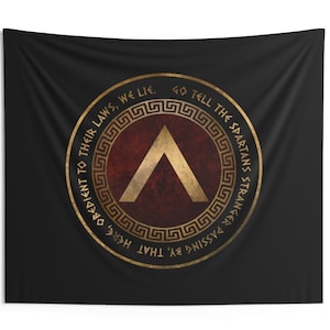 May include: A black tapestry featuring a gold circle with a red shield and a gold chevron. The circle has a gold Greek key border and text that reads "Go tell the Spartans stranger passing by, that here, obedient to their laws, we lie."